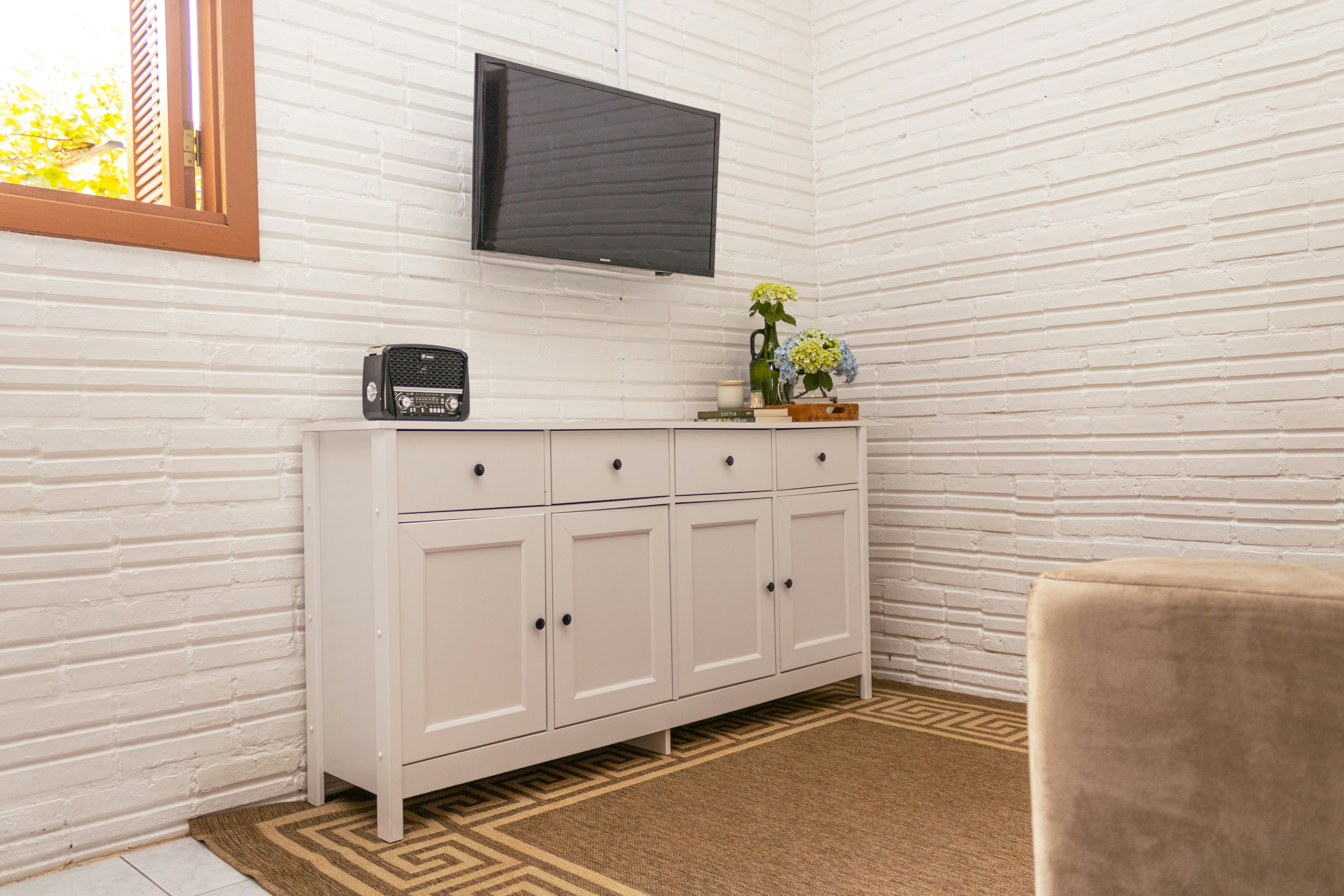 White sideboard with a television mounted above.