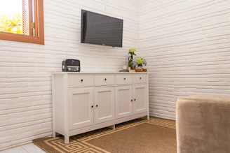 White sideboard with a television mounted above.