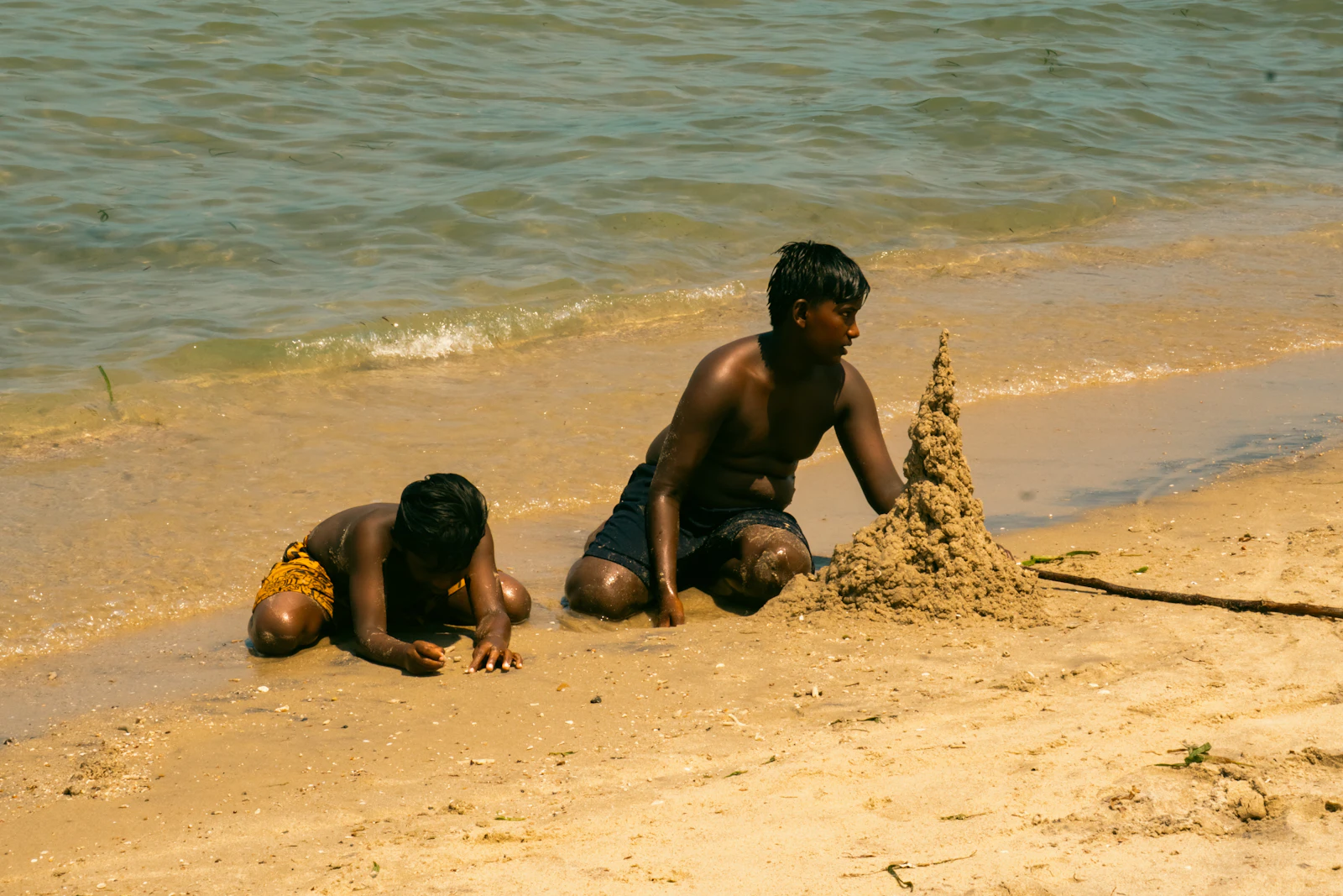 Mother laughing with two children on a sandy beach