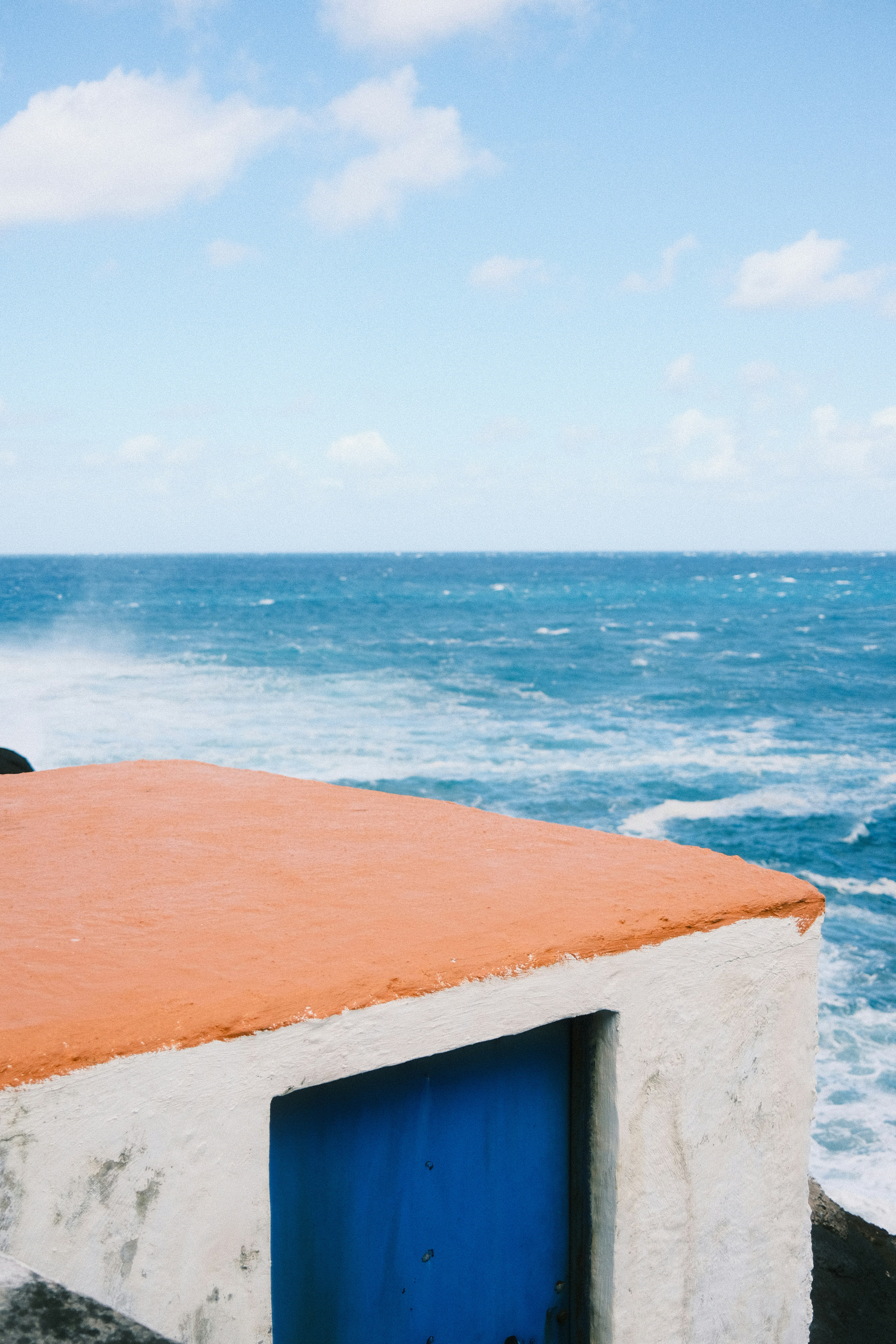 Pequeno edifício com porta azul à beira-mar