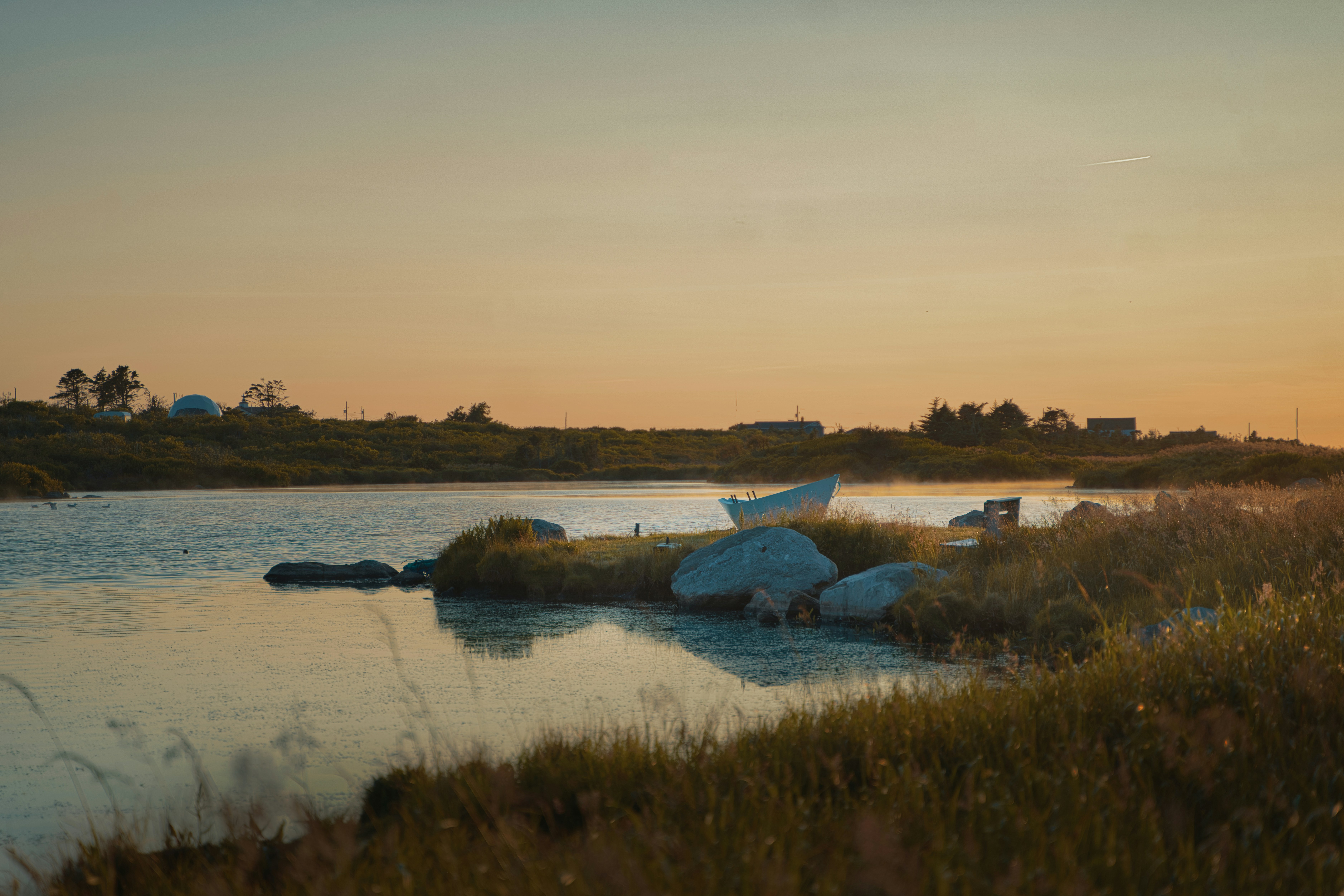 Calm lake with a small boat at sunset.