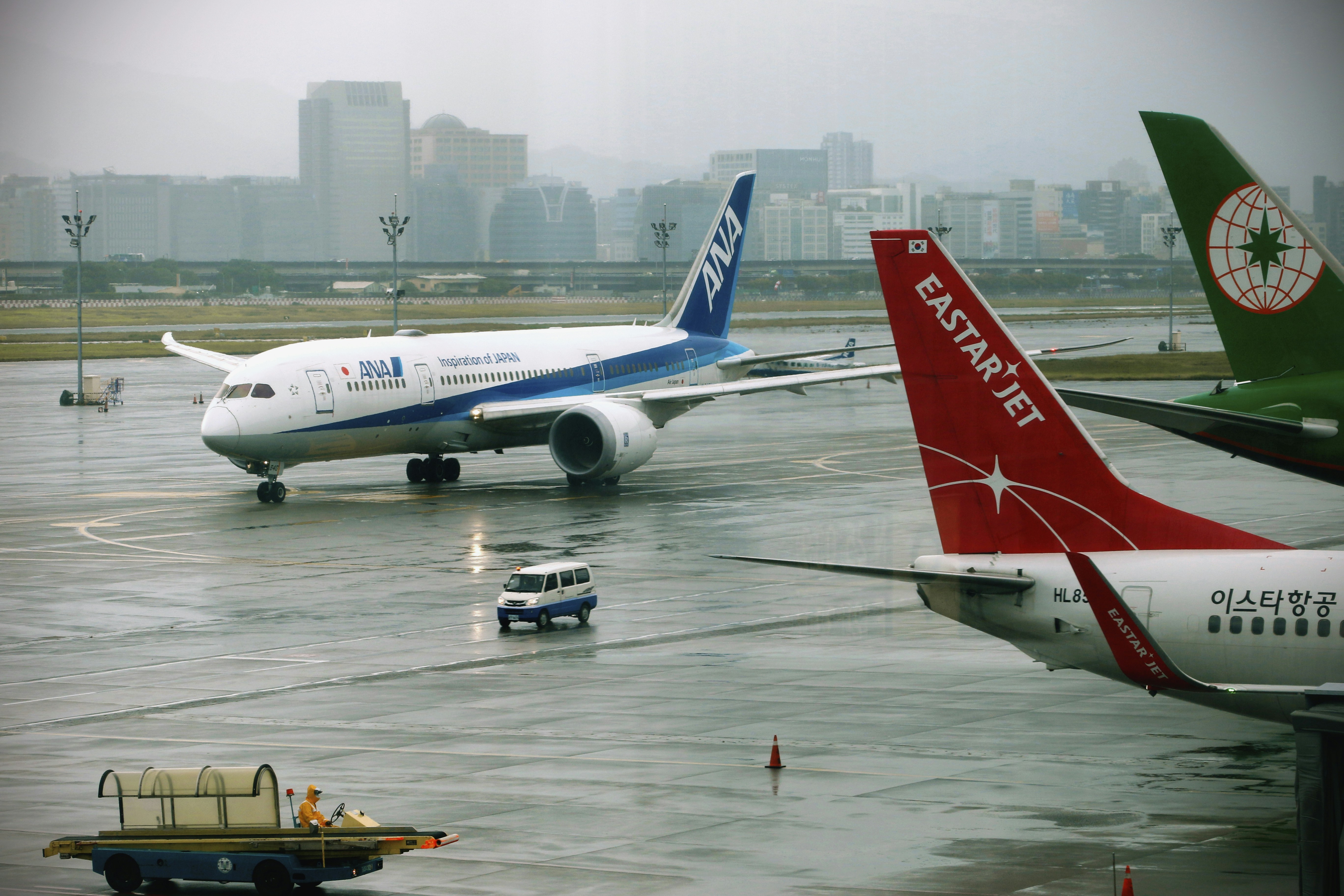 Aviones en una pista mojada con edificios de fondo