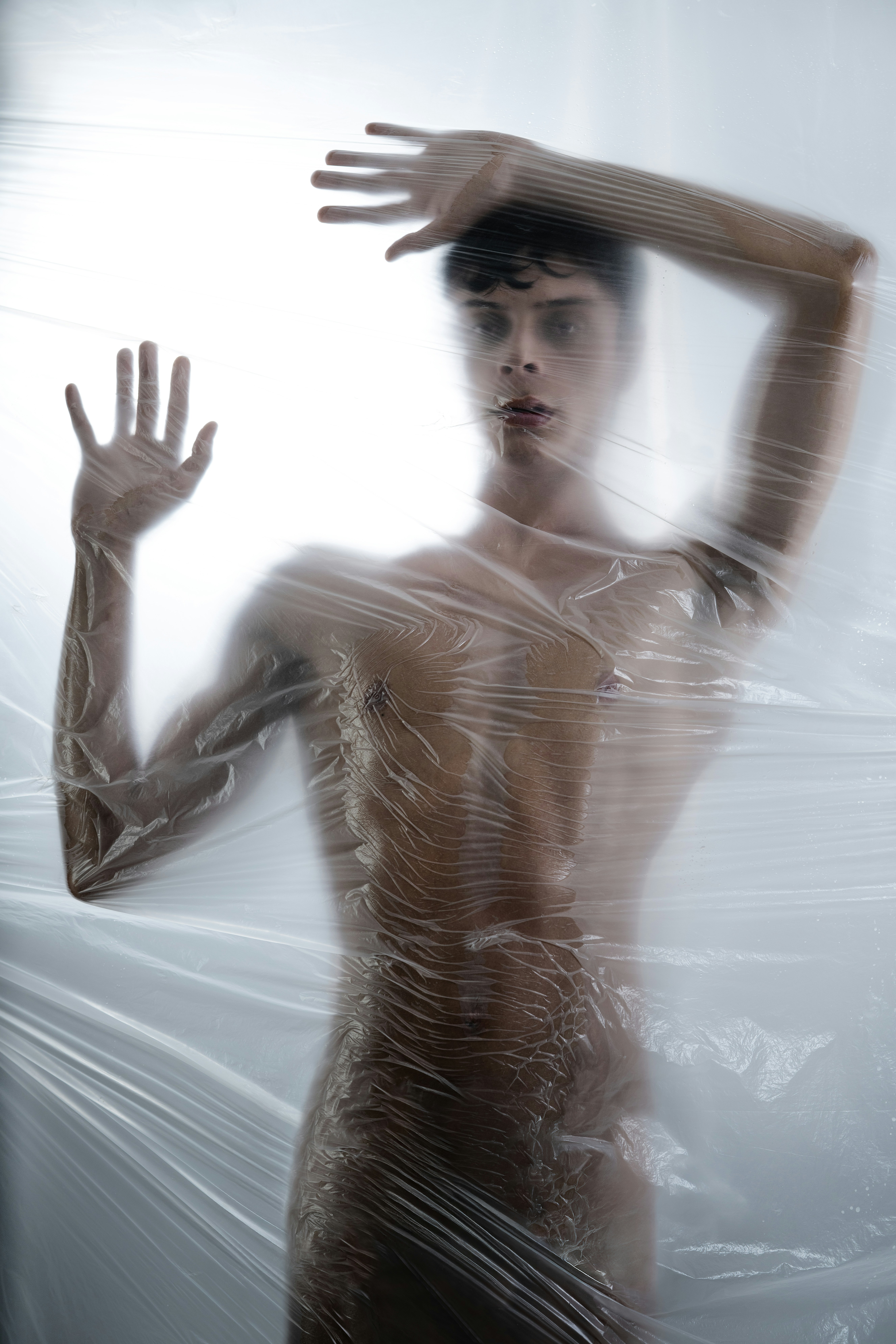 Mann in Plastikfolie gewickelt, Hände erhoben