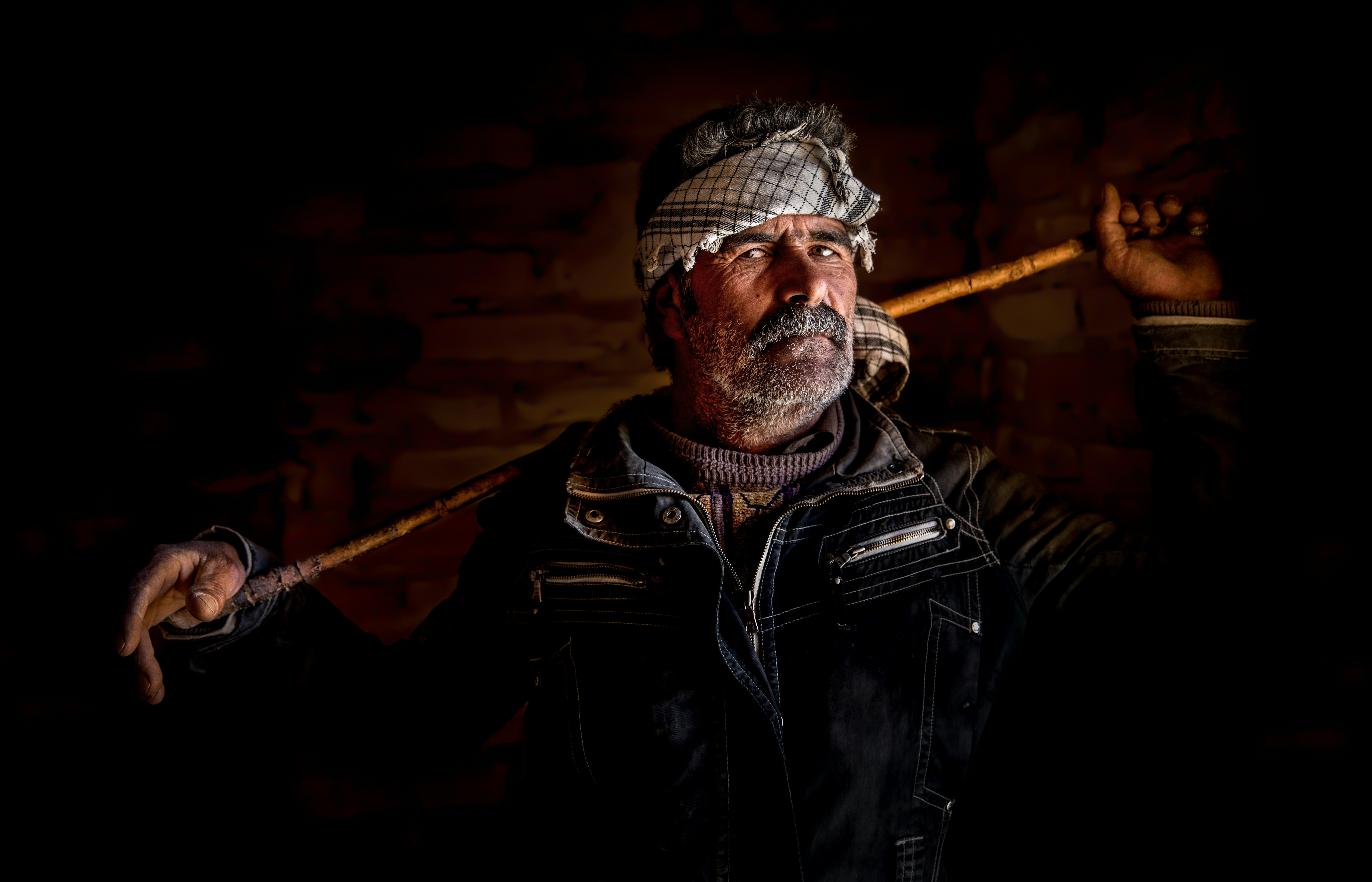 Man with a stick wearing a headscarf