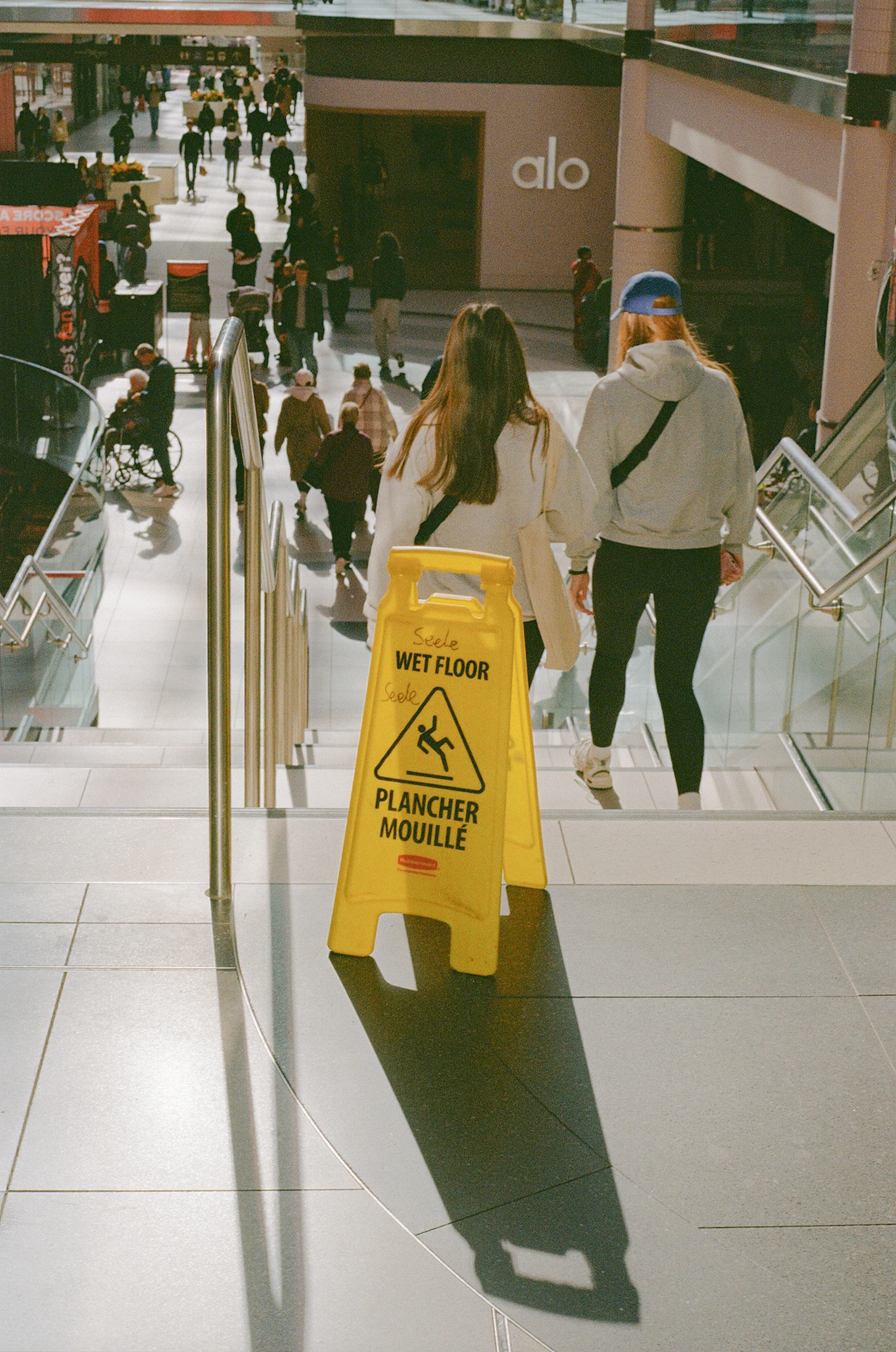 People walking near a wet floor warning sign