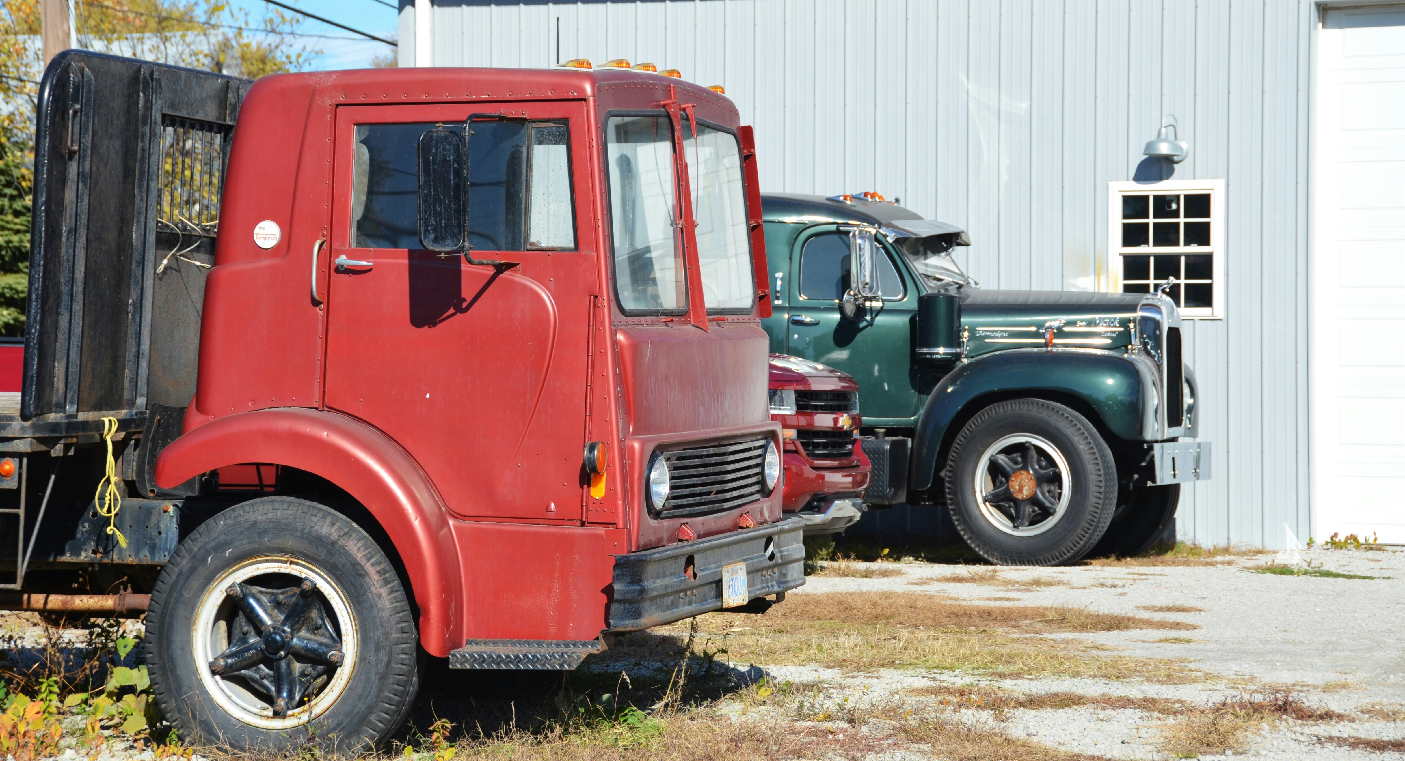 Two old trucks parked outside a building.