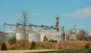 Industrial grain silos under a clear blue sky.