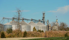 Industrial grain silos under a clear blue sky.
