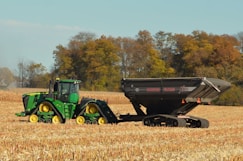 Tractor pulling a large trailer in a dry field.