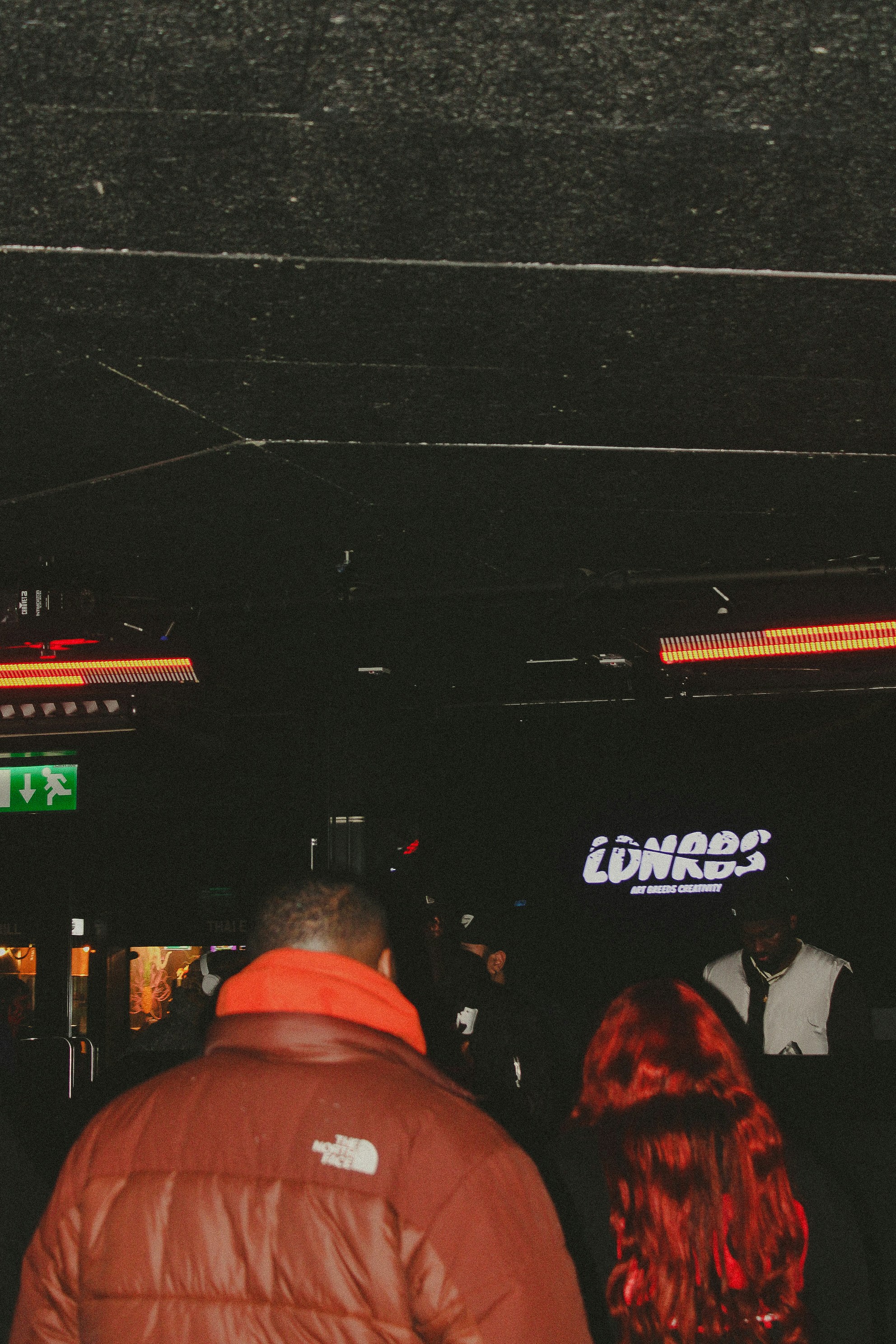 People gathered in a dark club beneath neon lights