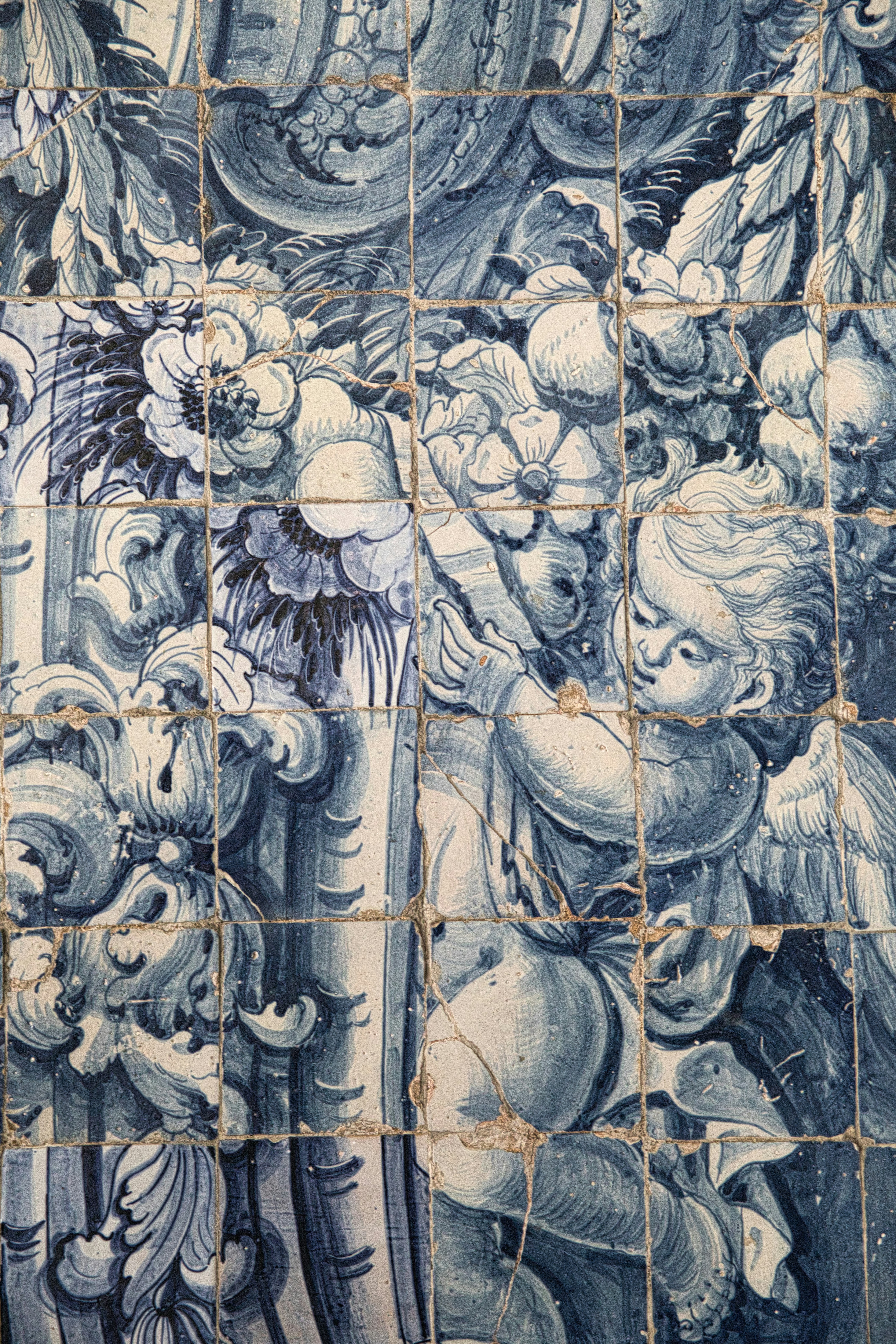 Blue and white tiled mural with cherub and floral motifs.