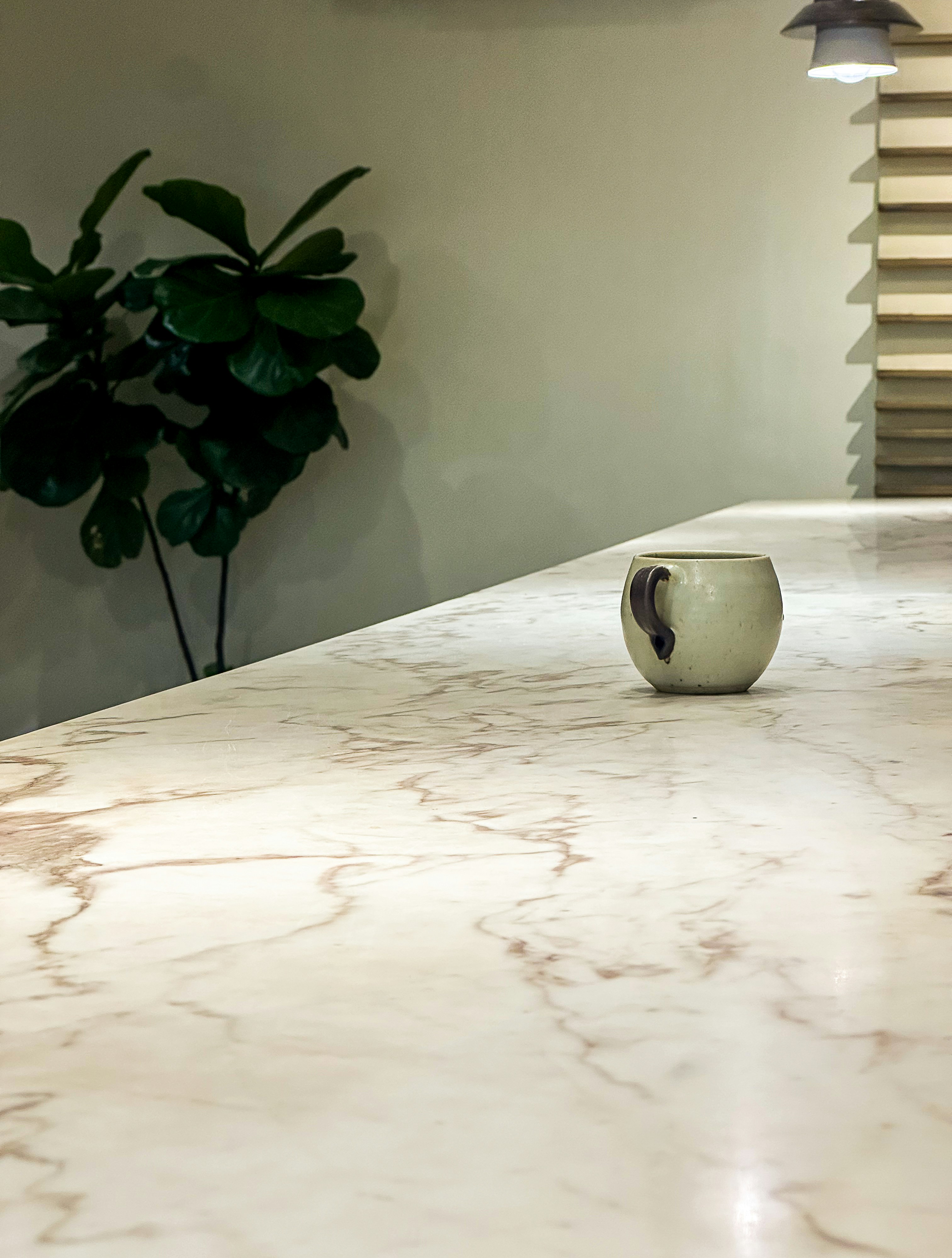 Une seule tasse repose sur un comptoir en marbre.