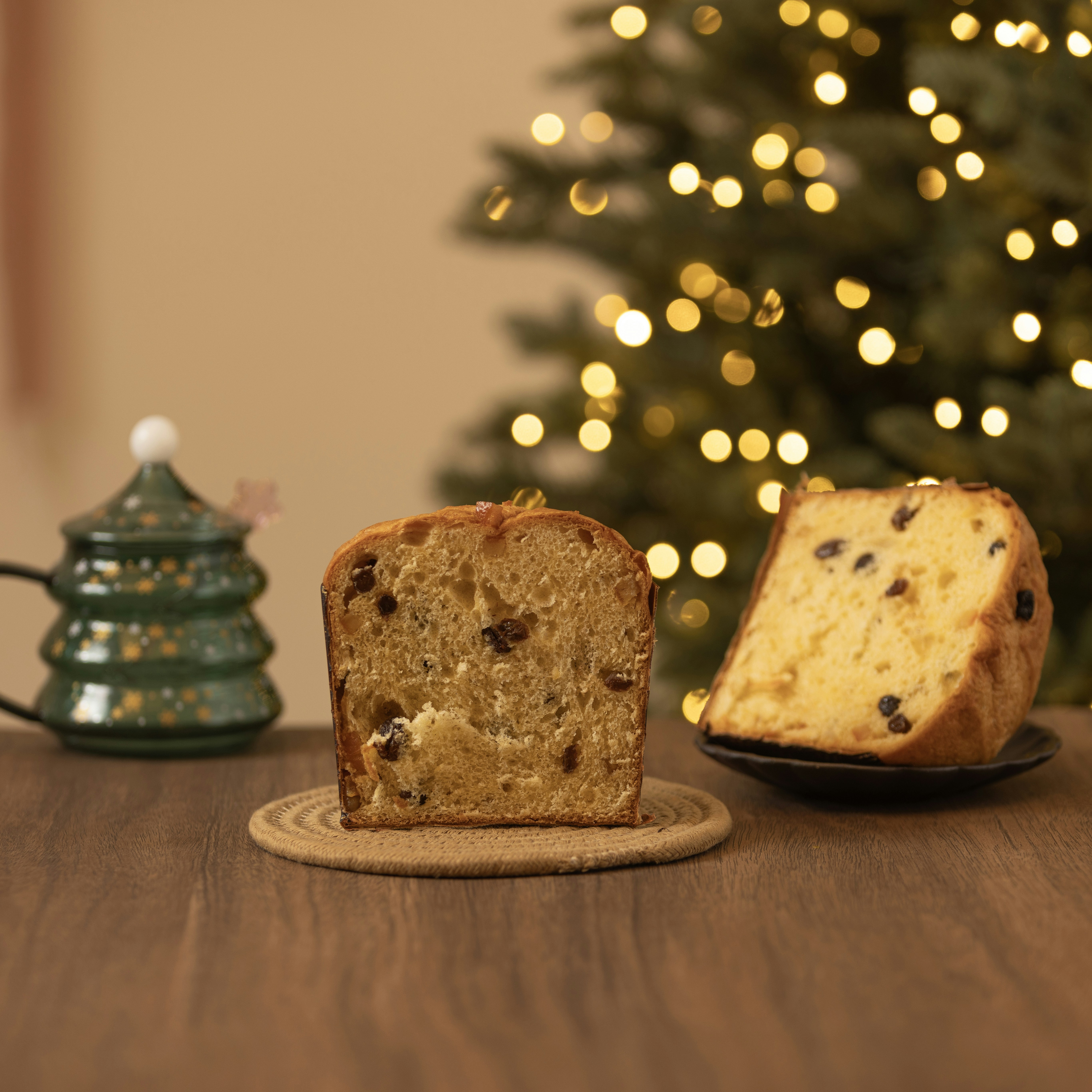 Sliced panettone with raisins displayed on wooden coaster with holiday decorations