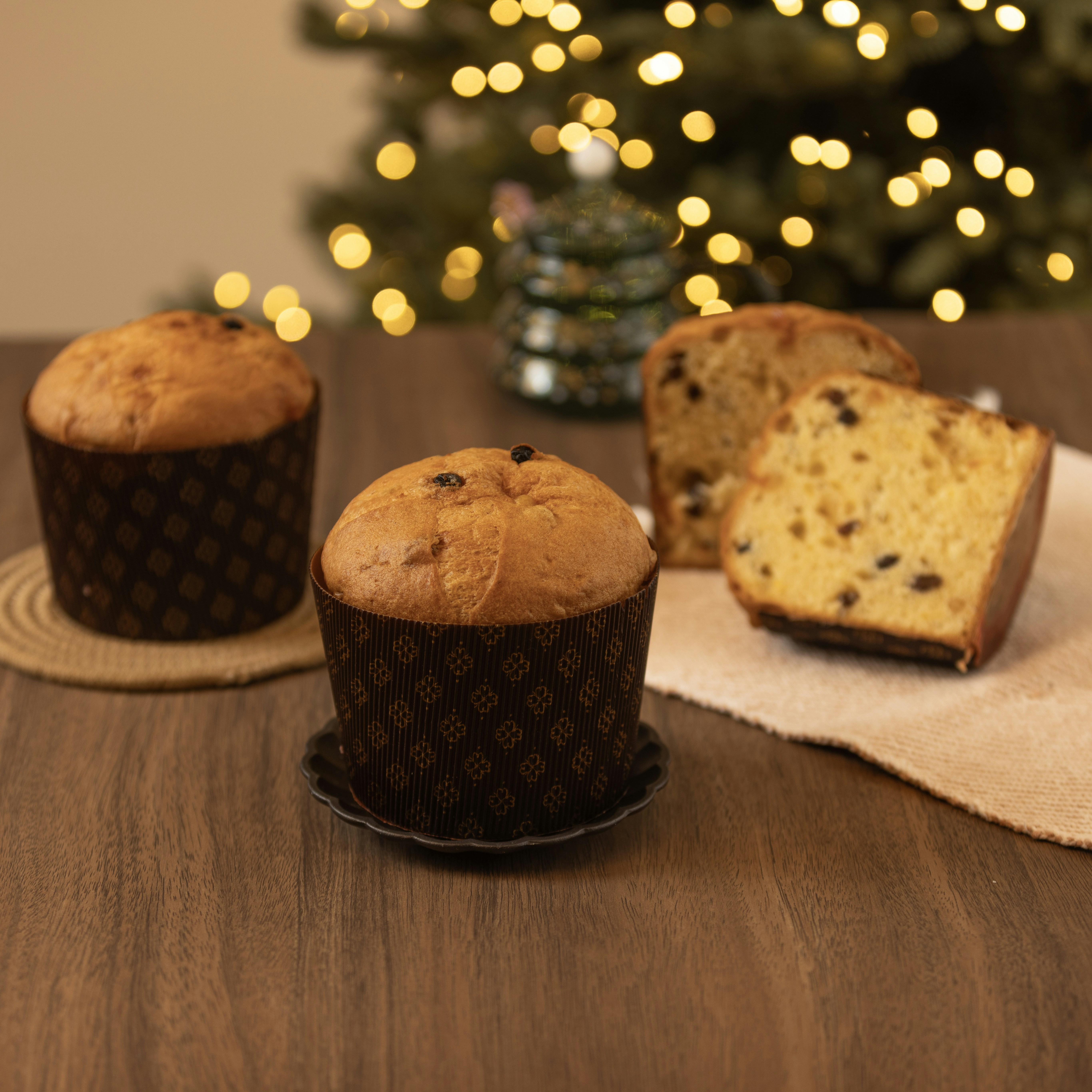 Panettone cakes with chocolate chips on a wooden table.