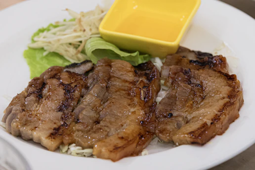 Grilled pork chops with a side of lettuce and sauce.