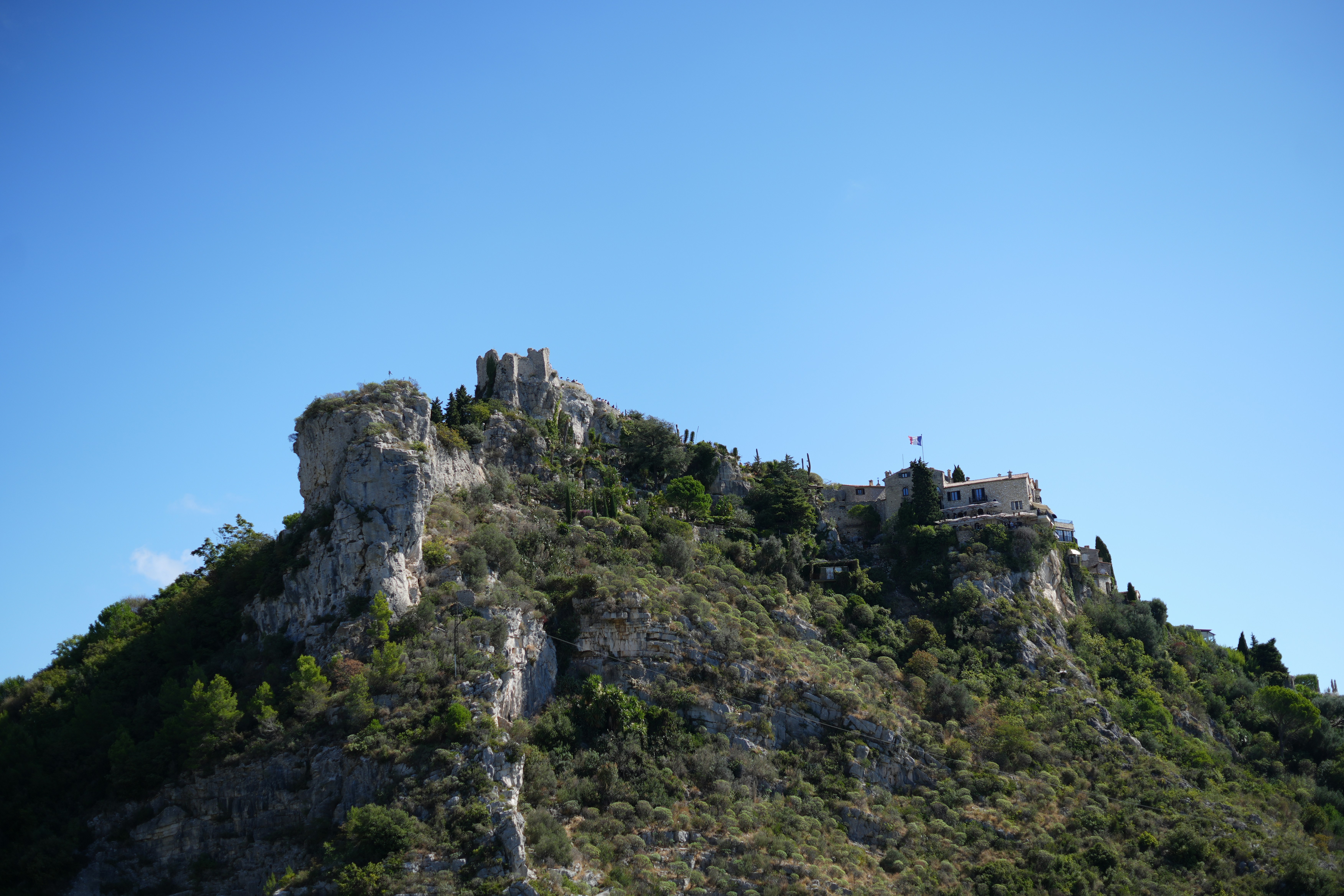 Ancient castle ruins atop a rocky, tree-covered mountain.