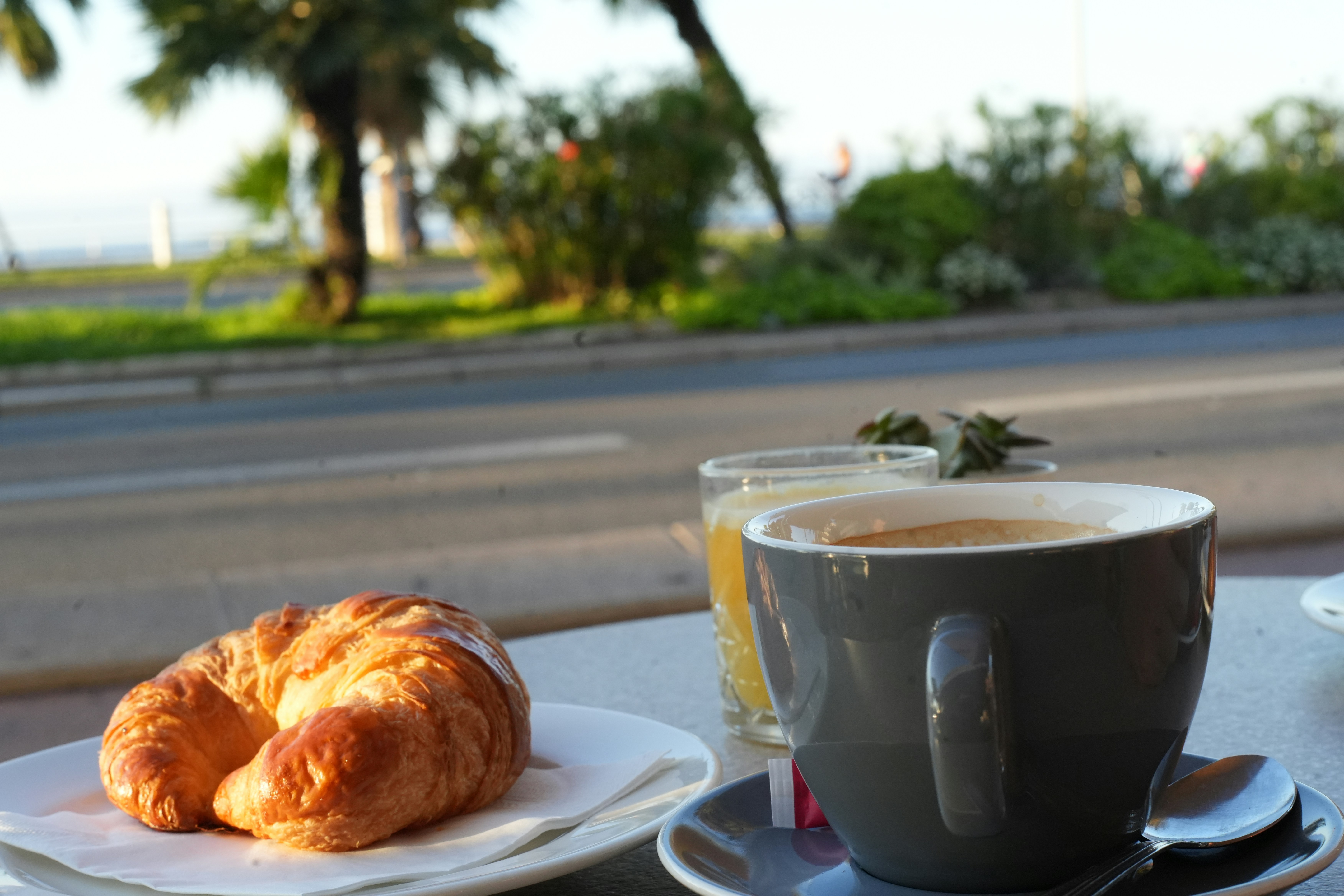 Croissant and coffee on a table outdoors.