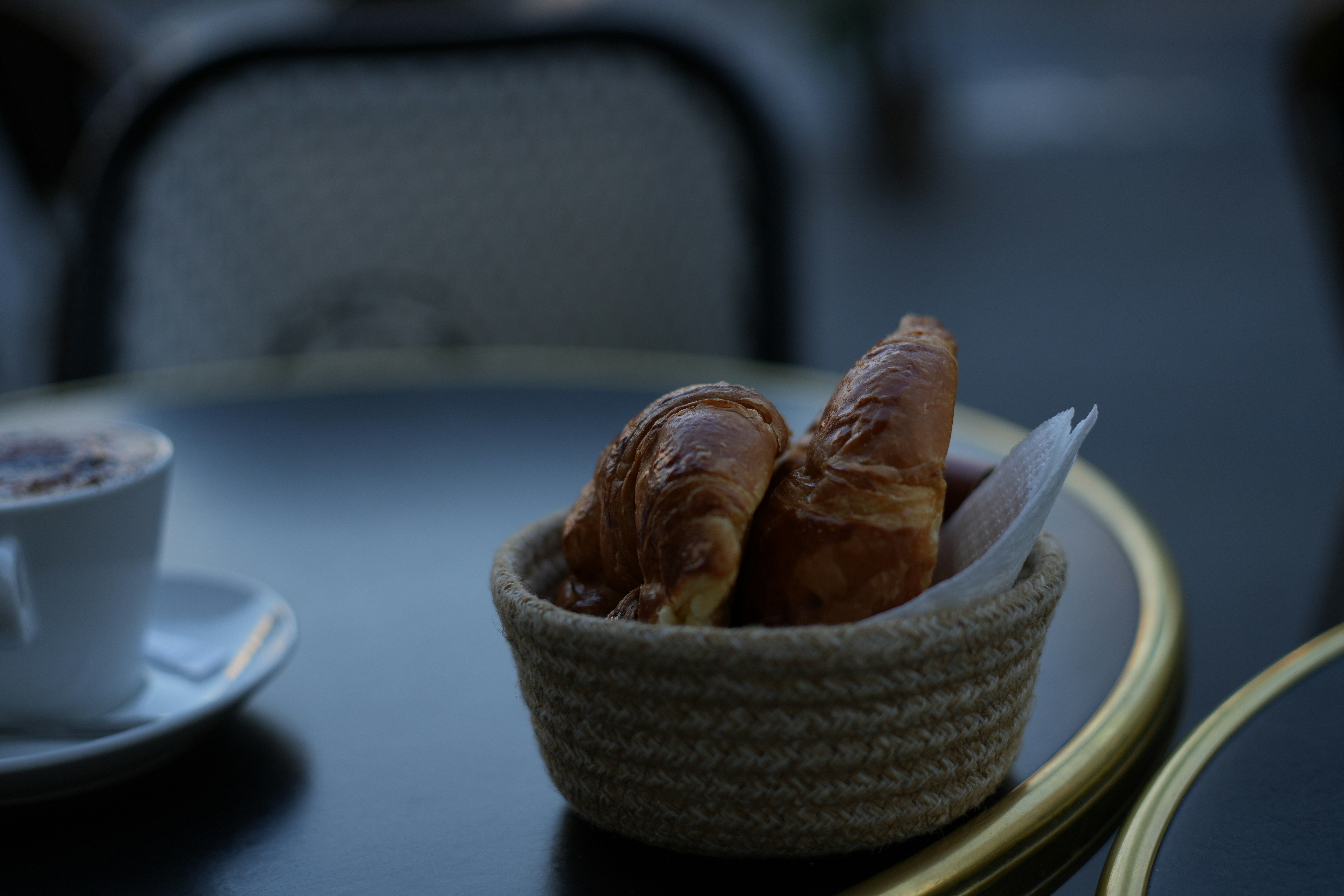 Croissants in a basket with a cup of coffee.