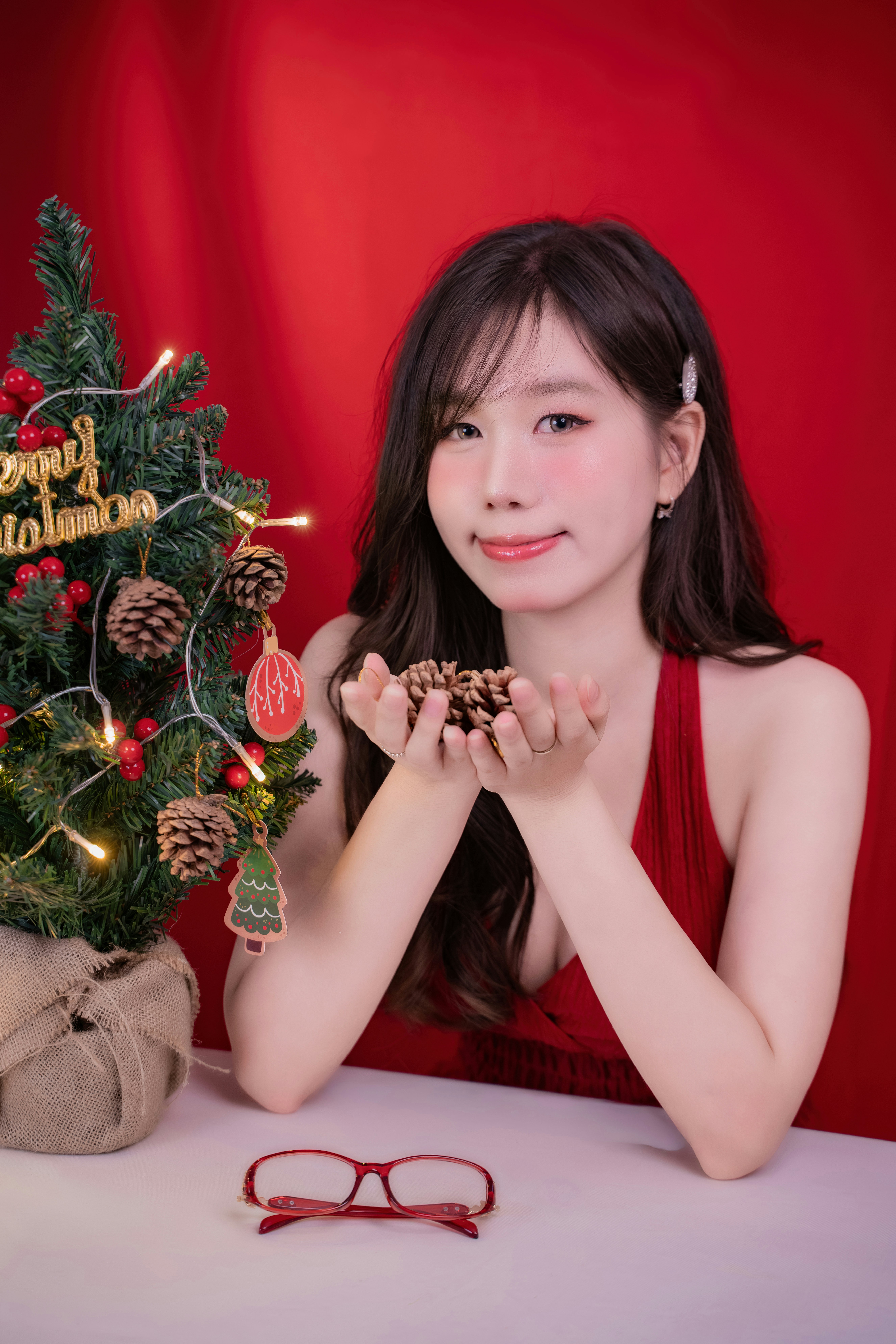 Young woman holding pinecones near christmas tree