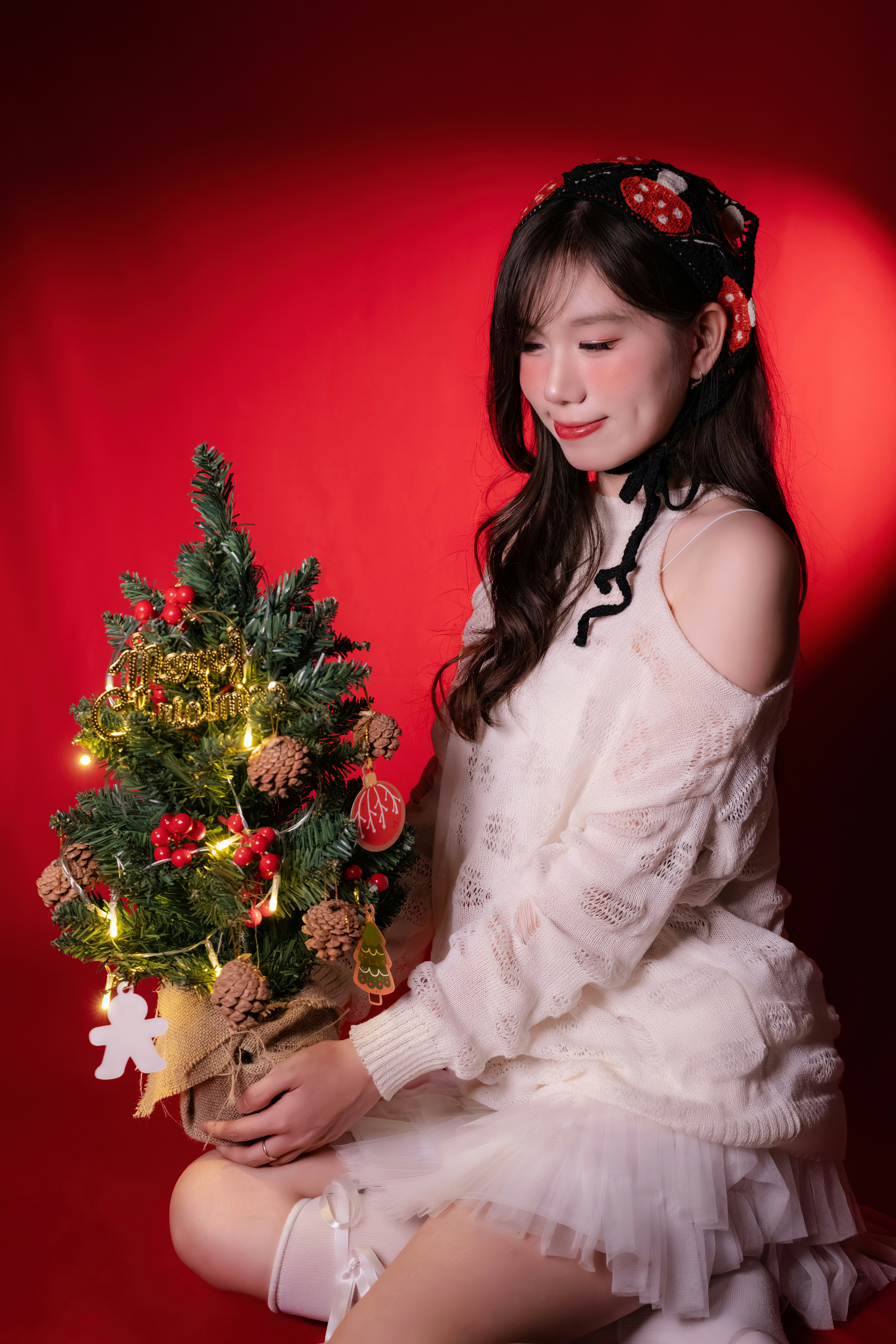 Young woman holding a small decorated christmas tree.