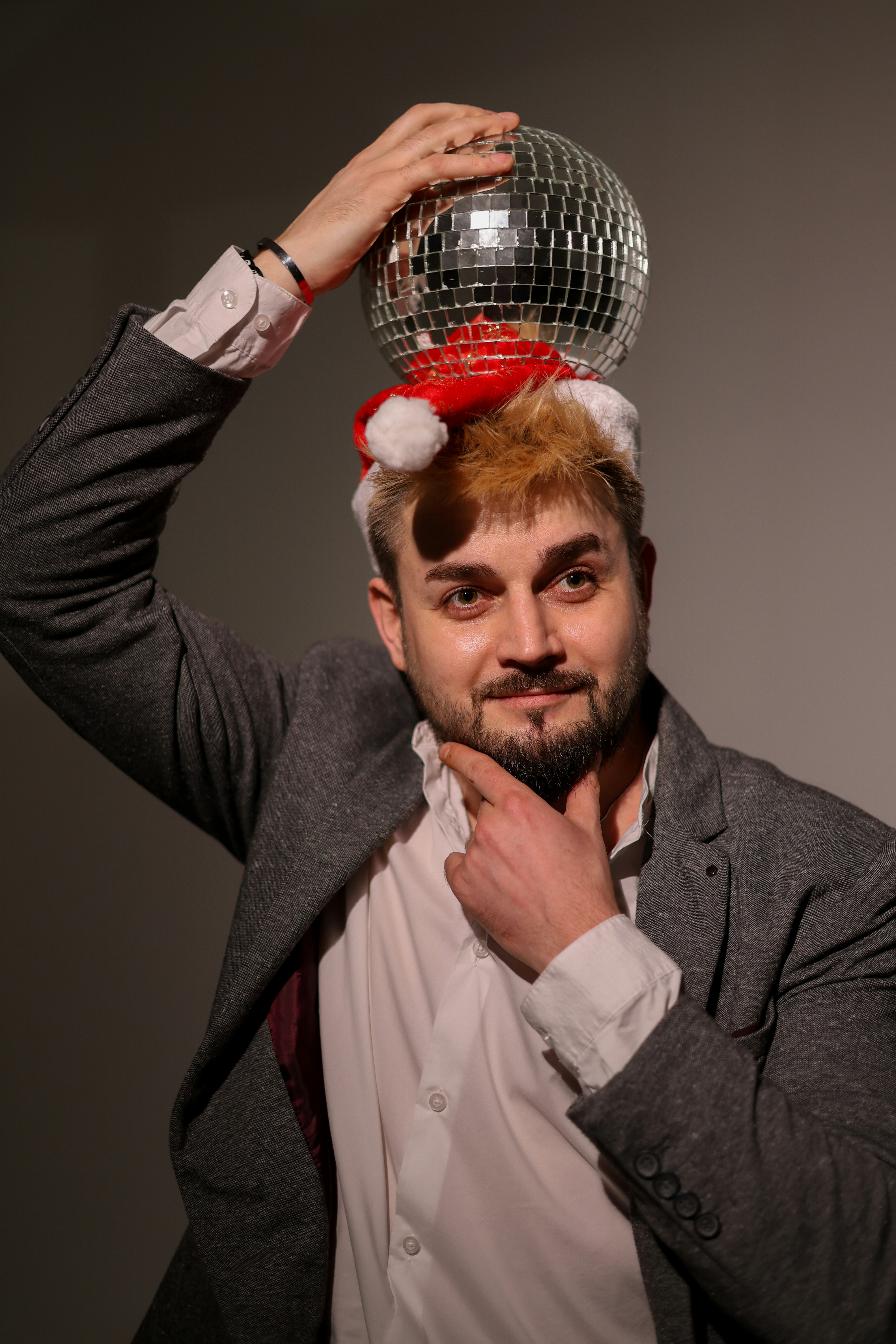 Man wearing a santa hat and holding a disco ball