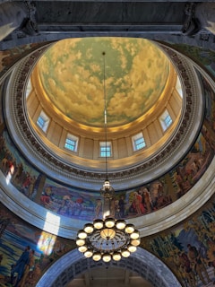 Intricate dome interior with murals and chandelier.