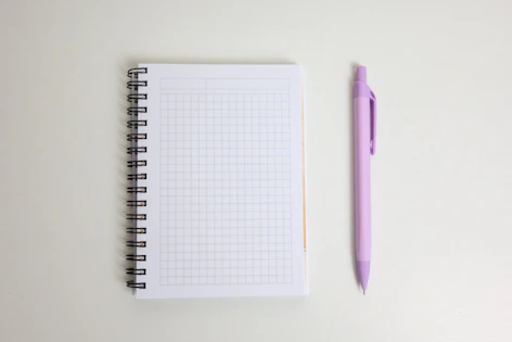 A blank notebook and a purple pen