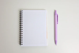 A blank notebook and a purple pen