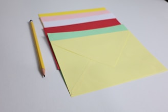 Colored envelopes and a pencil on a white surface