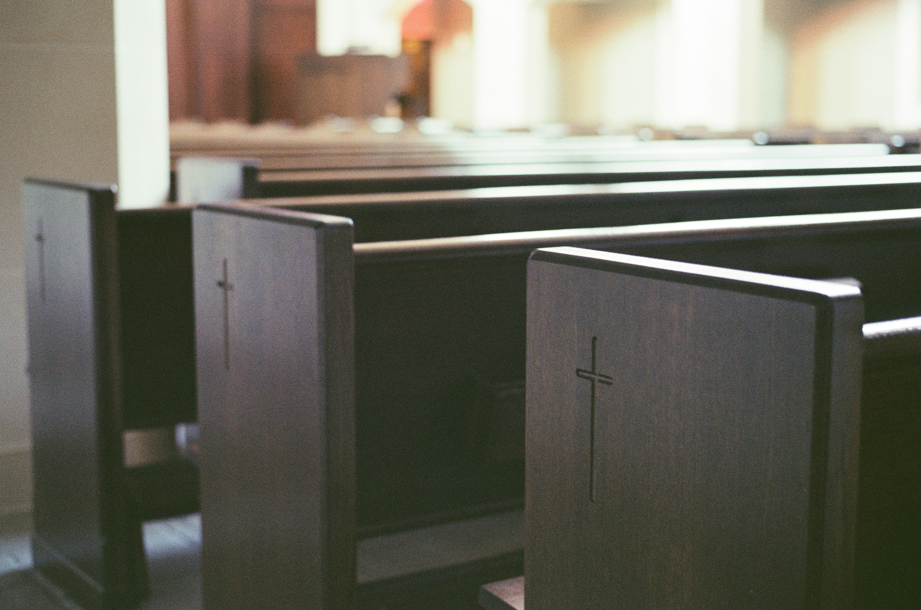 Empty church pews with crosses visible crosses.