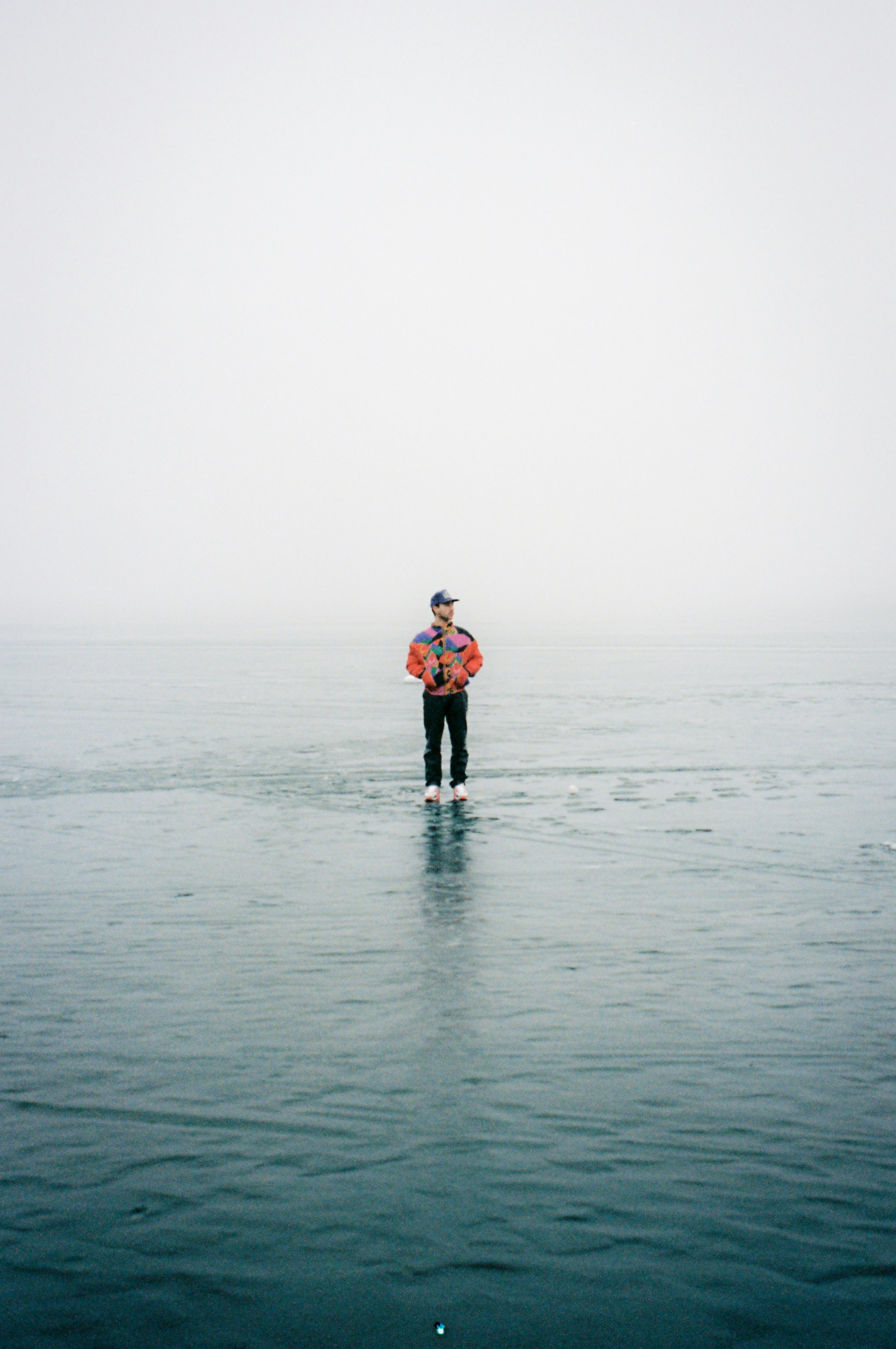 Man standing on a frozen lake with fog