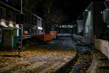 Street at night with fallen leaves and construction.