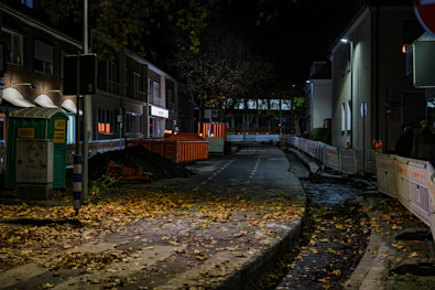 Street at night with fallen leaves and construction.