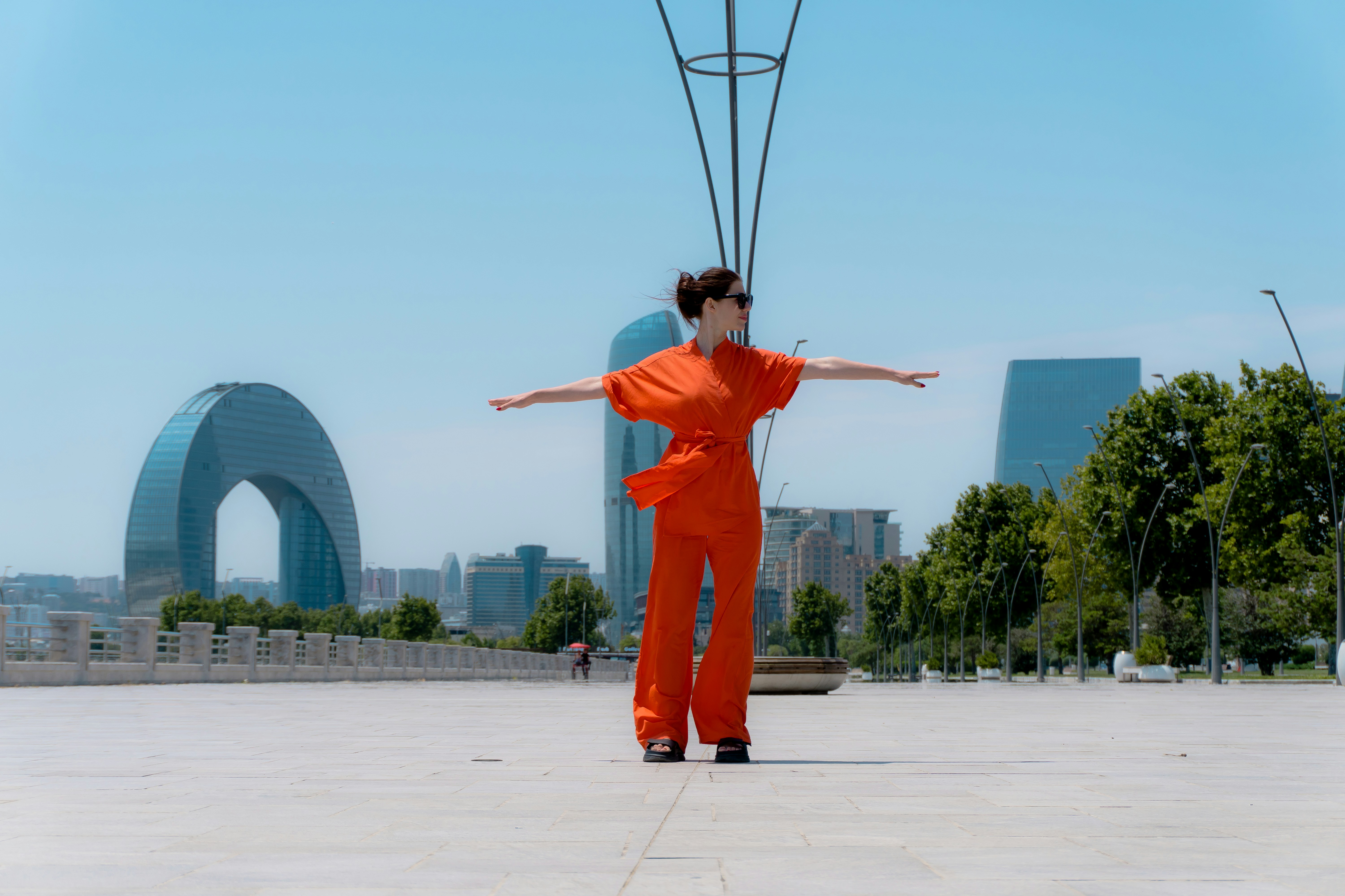 Frau im orangefarbenen Overall mit ausgestreckten Armen im Freien