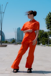 Woman in orange co-ord posing outdoors with city skyline