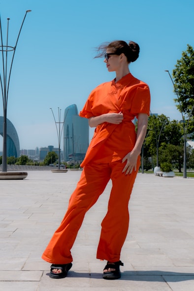 Woman in orange co-ord posing outdoors with city skyline