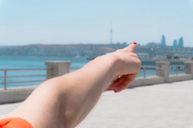 Arm pointing towards a city skyline by the water.
