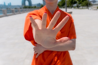 Woman in orange shirt holds up hand