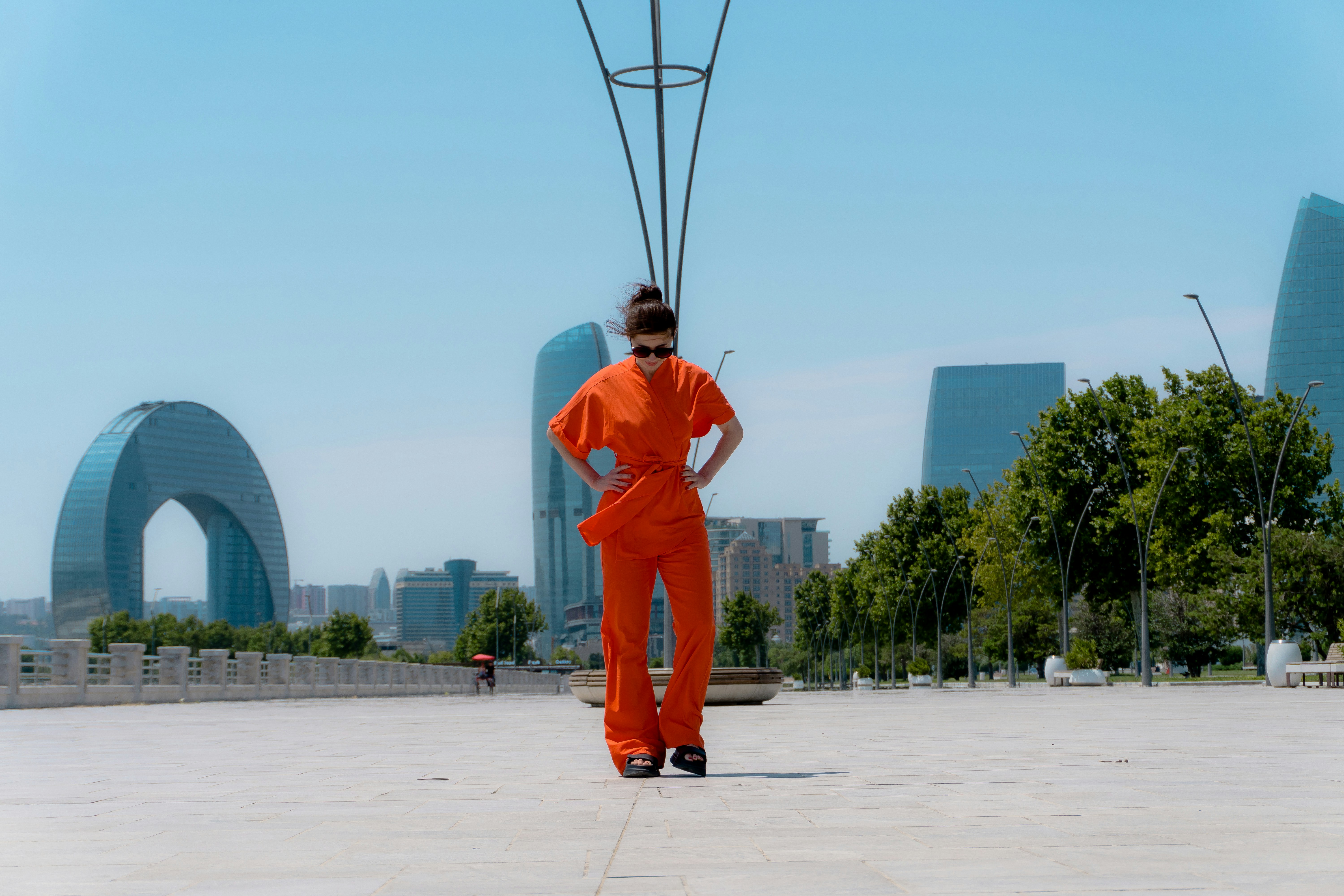 사진 찍을 때 포즈 고민 안 나는 기본 공식 - Woman in orange jumpsuit stands on plaza with cityscape background