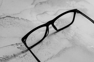 Black-rimmed glasses resting on a marbled surface
