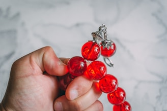 Hand holding a string of red amber beads