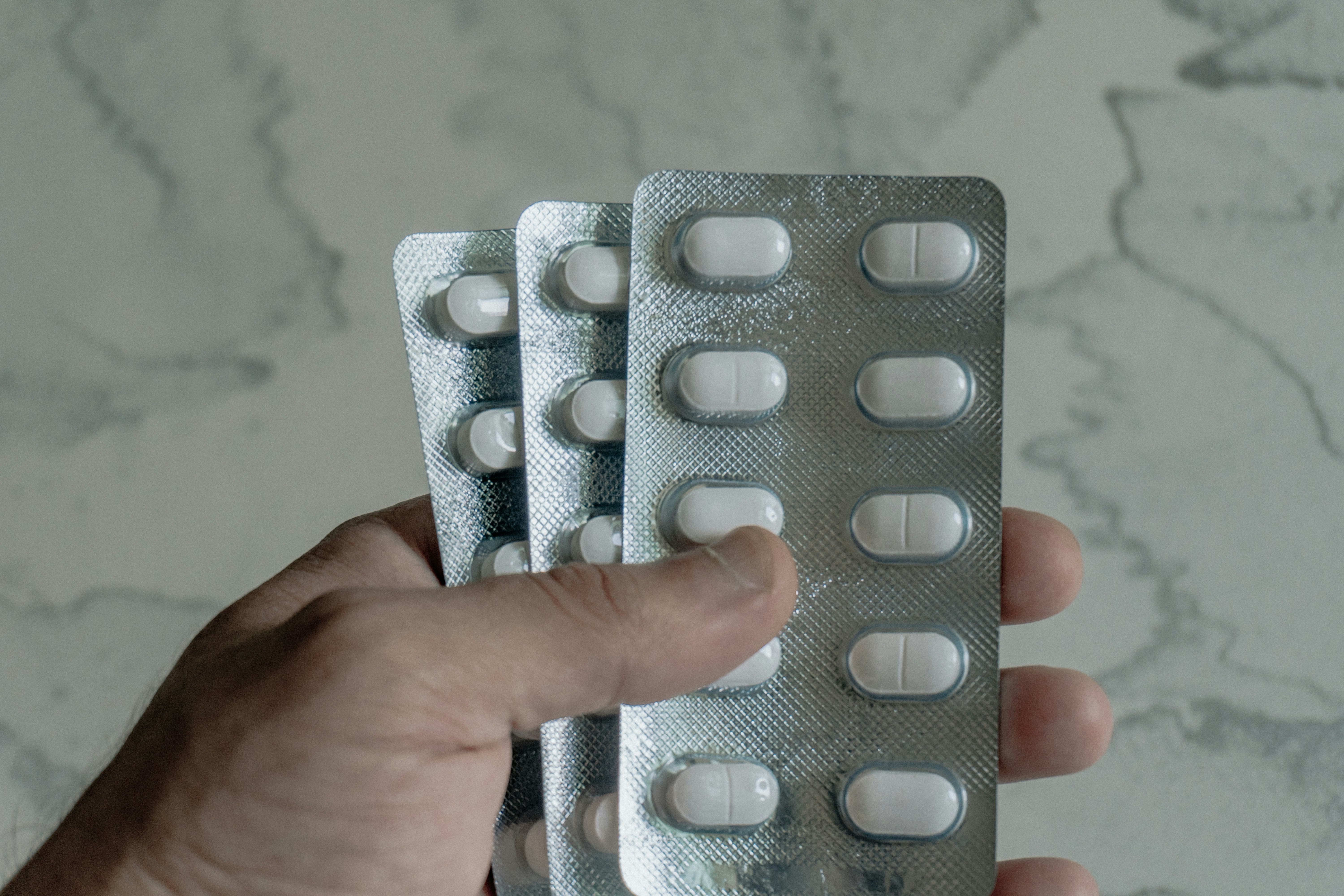 Hand holding blister packs of white pills