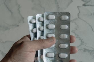 Hand holding blister packs of white pills