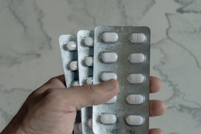 Hand holding blister packs of white pills