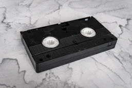 A black vhs tape on a marble background