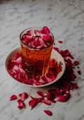 A glass of amber liquid with rose petals