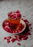 A glass of amber liquid with rose petals