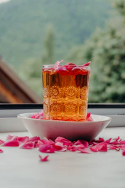 A glass of amber liquid with rose petals