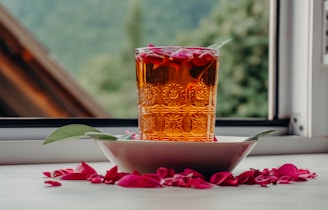 A glass of amber liquid with rose petals.