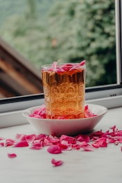 Glass of amber liquid with pink rose petals